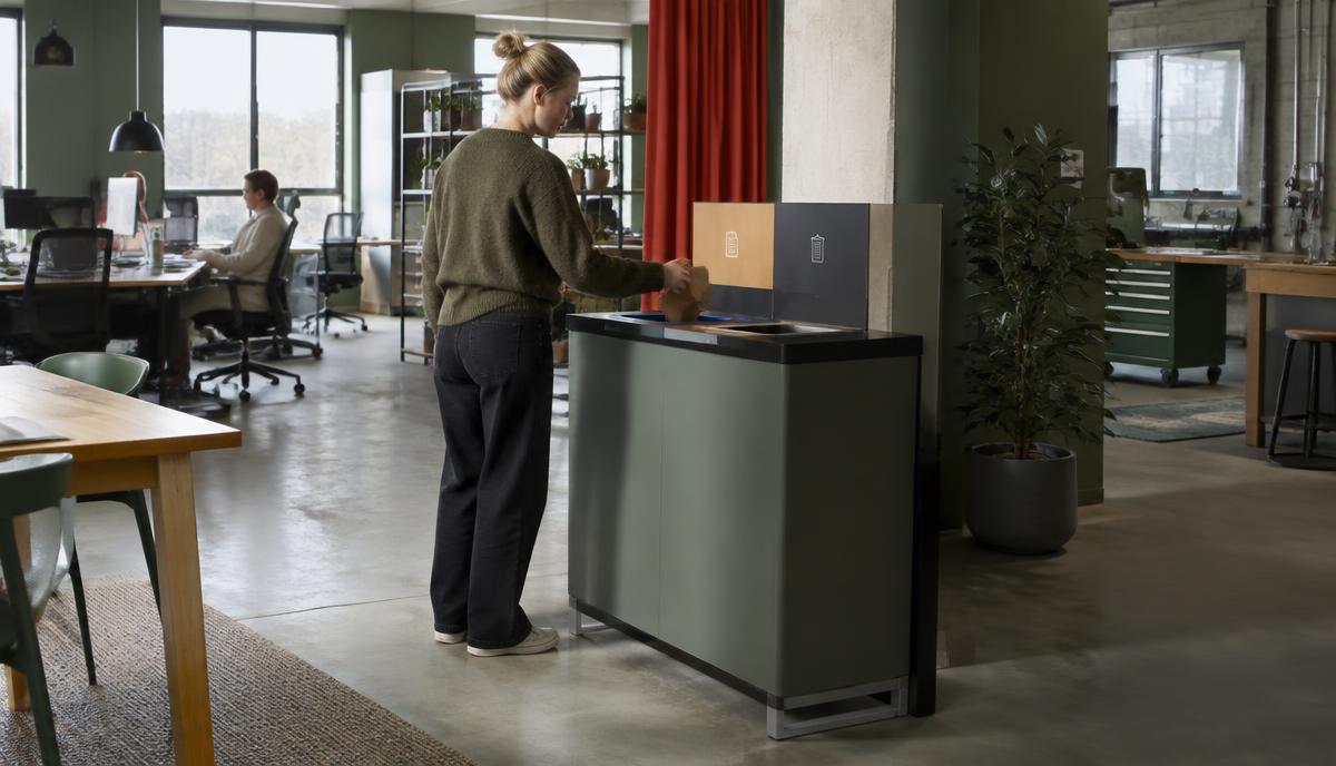 Medarbetare använder en central källsorteringsstation på arbetsplatsen